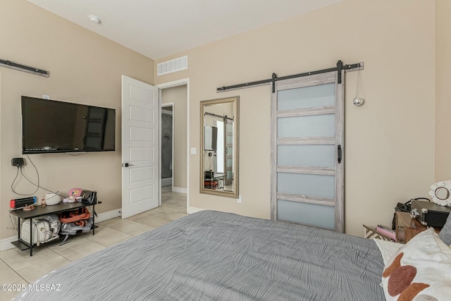 bedroom with light tile patterned floors, a barn door, visible vents, and baseboards