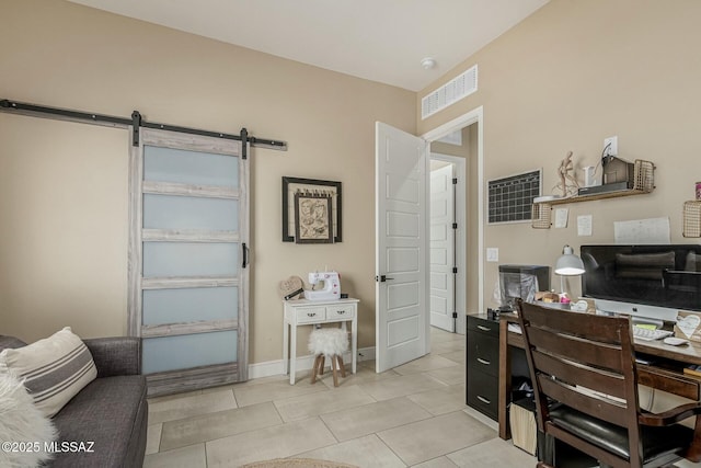 office with a barn door, light tile patterned flooring, visible vents, and baseboards