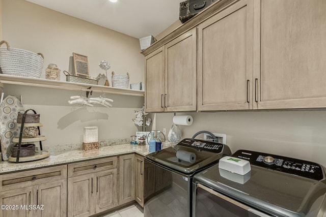 clothes washing area featuring cabinet space, washing machine and clothes dryer, and light tile patterned floors