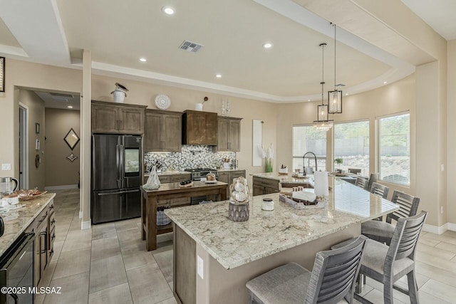 kitchen with decorative backsplash, a large island, a tray ceiling, smart refrigerator, and a sink