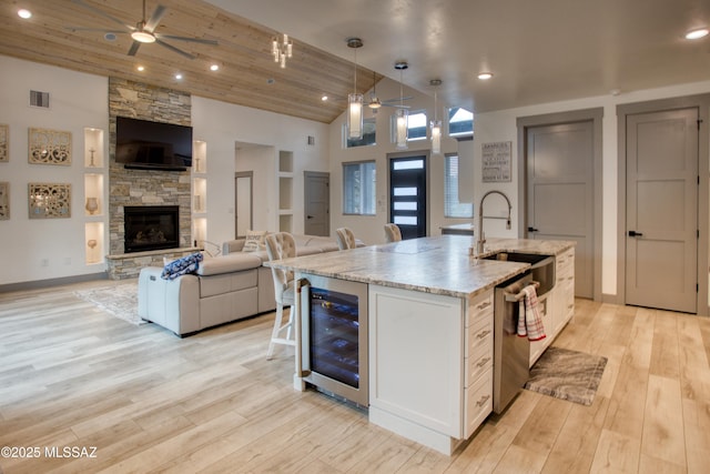 kitchen with beverage cooler, a ceiling fan, open floor plan, and a sink