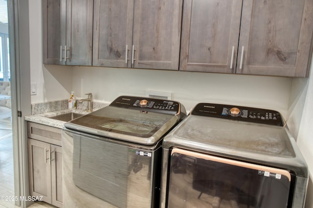 laundry room with washing machine and clothes dryer, a sink, and cabinet space