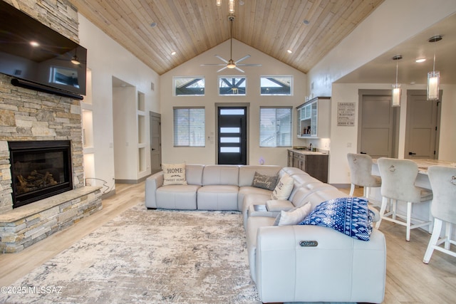 living room with a fireplace, a ceiling fan, high vaulted ceiling, light wood-type flooring, and wooden ceiling