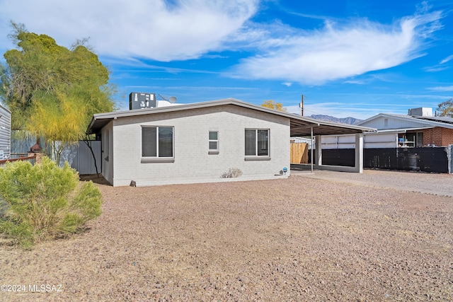 rear view of property featuring a carport, brick siding, fence, and driveway