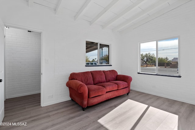 living room with brick wall, high vaulted ceiling, wood finished floors, and beam ceiling