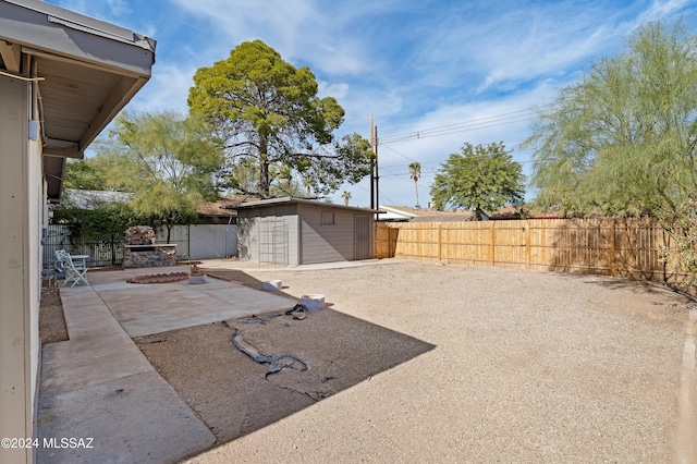 view of yard featuring a patio area, a fenced backyard, a storage shed, and an outbuilding