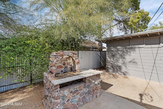 exterior space with a stone fireplace and fence