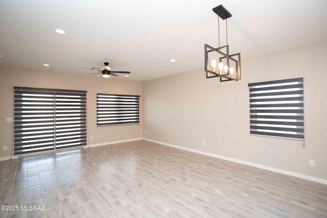 unfurnished room featuring wood finished floors, recessed lighting, and ceiling fan with notable chandelier