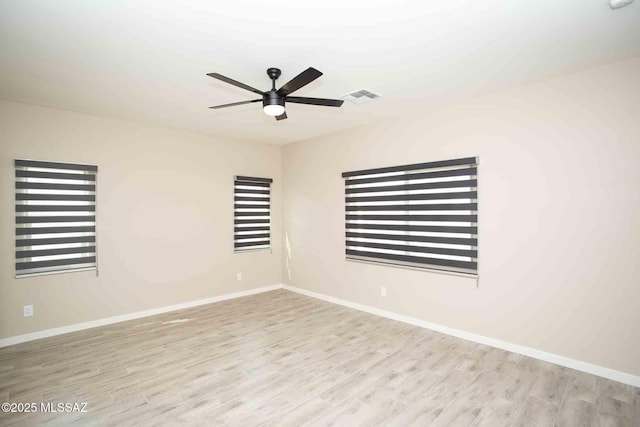 empty room featuring wood finished floors, visible vents, ceiling fan, and baseboards