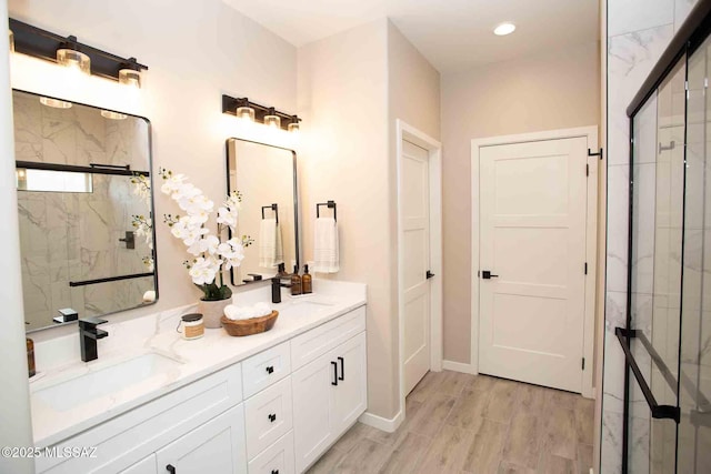 full bathroom with a marble finish shower, a sink, double vanity, and wood finished floors