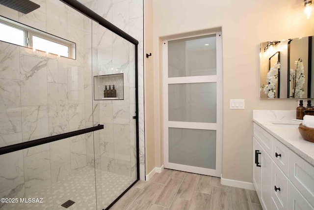 full bathroom featuring a marble finish shower, wood finished floors, vanity, and baseboards