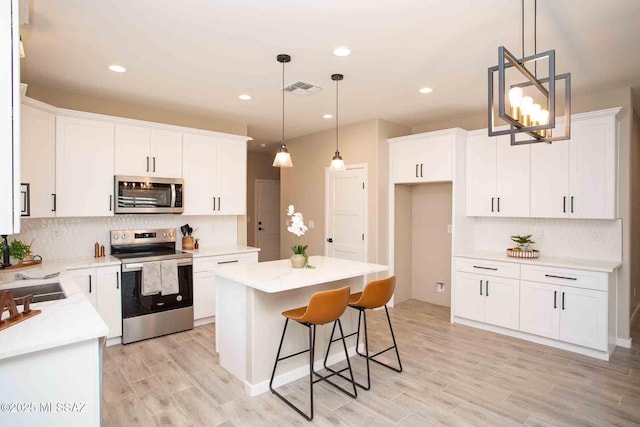 kitchen featuring stainless steel appliances, a kitchen island, and white cabinets