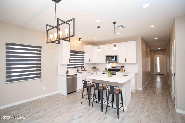 kitchen featuring a breakfast bar, visible vents, light countertops, white cabinets, and appliances with stainless steel finishes