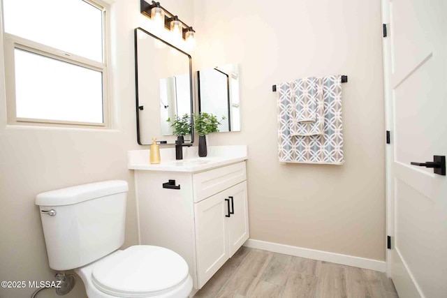 bathroom with baseboards, wood finished floors, toilet, and vanity