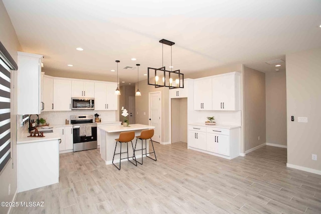 kitchen featuring stainless steel appliances, light wood-type flooring, white cabinetry, and a kitchen island