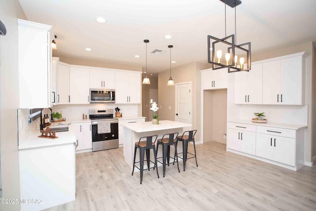 kitchen with white cabinets, appliances with stainless steel finishes, a kitchen island, and a sink