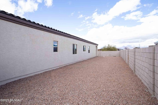 view of side of home featuring stucco siding and a fenced backyard