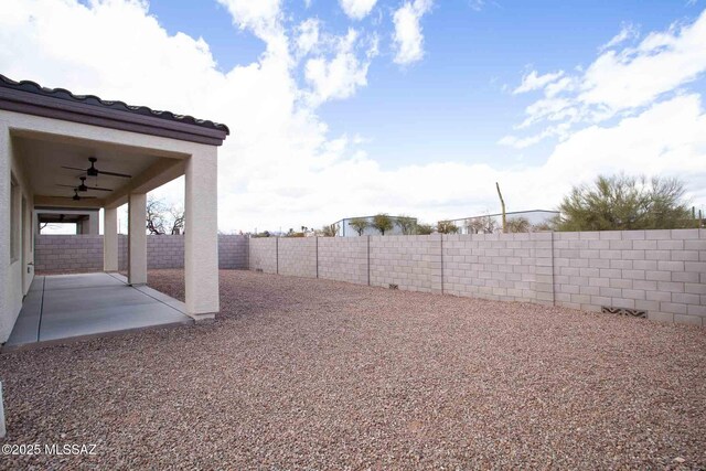 view of yard with a fenced backyard, a ceiling fan, and a patio area