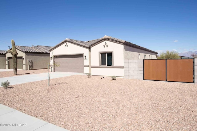 view of front of house featuring driveway, a tiled roof, stucco siding, and an attached garage