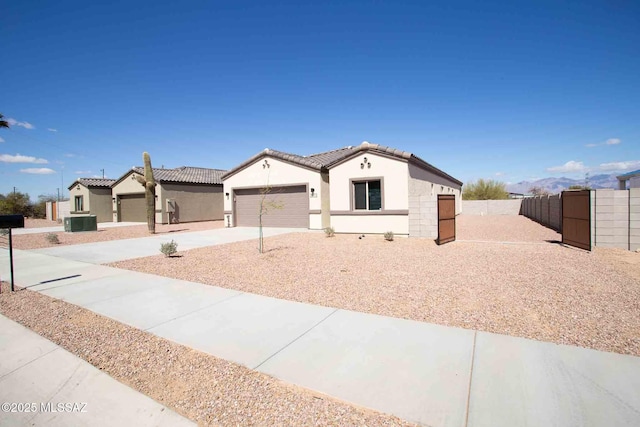 view of front facade with central air condition unit, a garage, concrete driveway, stucco siding, and fence