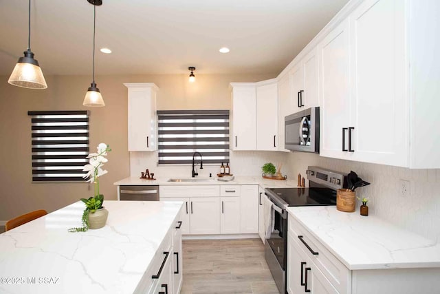 kitchen featuring hanging light fixtures, a sink, white cabinets, and stainless steel appliances