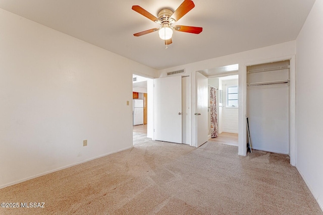 unfurnished bedroom featuring two closets, light colored carpet, visible vents, a ceiling fan, and freestanding refrigerator