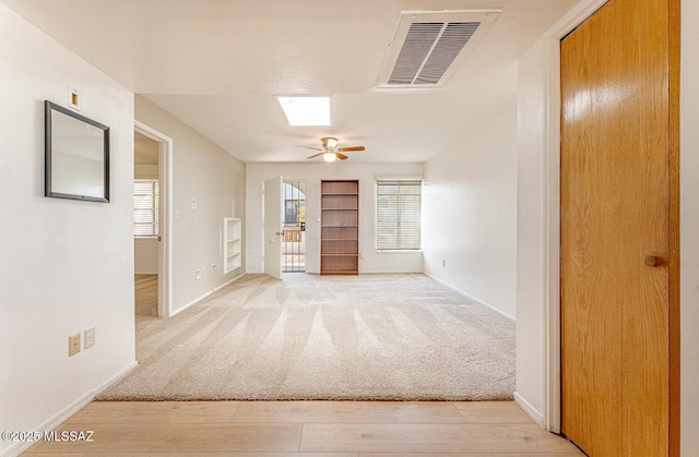 empty room featuring light carpet, ceiling fan, visible vents, and baseboards