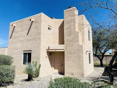 pueblo revival-style home featuring a chimney and stucco siding