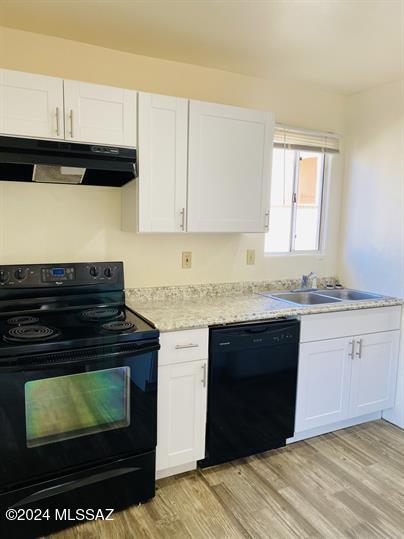 kitchen with under cabinet range hood, light countertops, black appliances, white cabinetry, and a sink