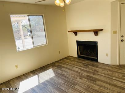 unfurnished living room with ceiling fan, a fireplace, and wood finished floors