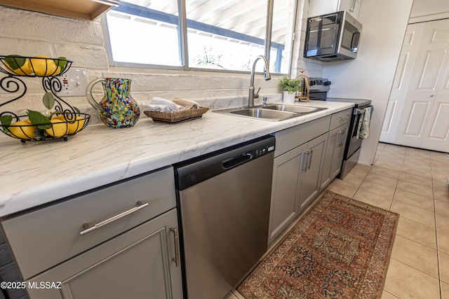 kitchen featuring a sink, gray cabinetry, light tile patterned flooring, and stainless steel appliances