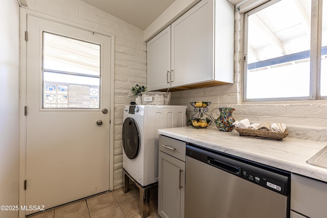 laundry area featuring light tile patterned flooring, laundry area, plenty of natural light, and washer / clothes dryer