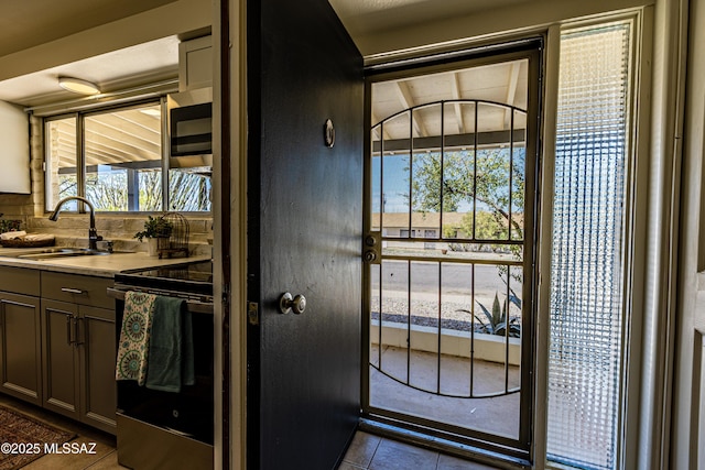 kitchen with dark tile patterned floors, light countertops, electric stove, and a sink