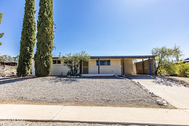 view of front of property featuring a carport, brick siding, and driveway