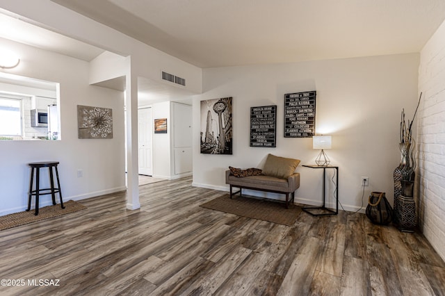 sitting room with lofted ceiling, dark wood-style floors, visible vents, and baseboards