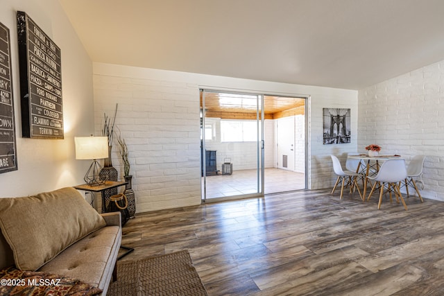 living area featuring wood finished floors and brick wall