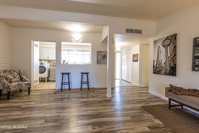 interior space featuring visible vents, baseboards, washer / dryer, and dark wood-style floors