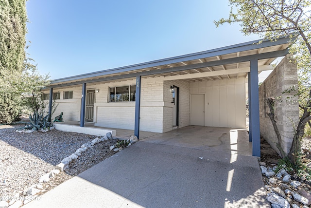 ranch-style house featuring an attached carport, concrete driveway, covered porch, and brick siding