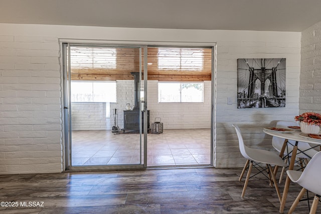 unfurnished dining area with brick wall, a wood stove, and wood finished floors