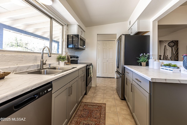 kitchen with light tile patterned flooring, a sink, gray cabinetry, appliances with stainless steel finishes, and tasteful backsplash