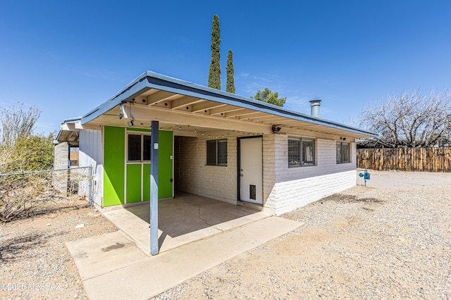 view of front of home with an attached carport, fence, brick siding, and driveway