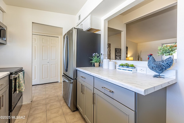 kitchen with light tile patterned floors, visible vents, stainless steel appliances, and gray cabinetry