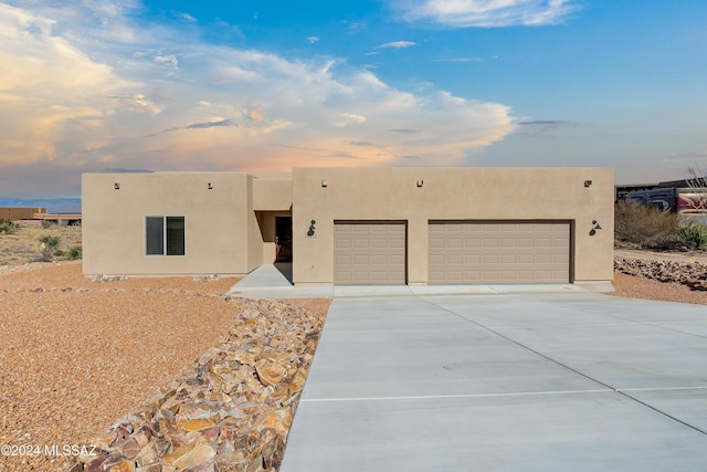 pueblo-style home featuring a garage, concrete driveway, and stucco siding