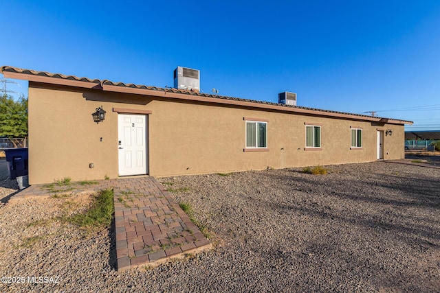 back of property featuring stucco siding, cooling unit, and a chimney