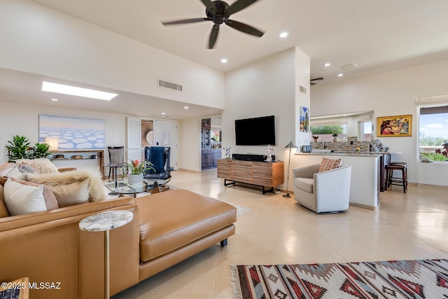 living area with visible vents, recessed lighting, a ceiling fan, and a towering ceiling