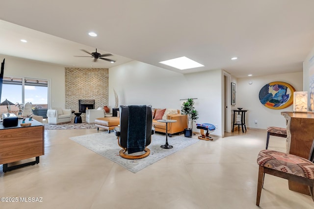 living area featuring finished concrete floors, recessed lighting, a fireplace, a skylight, and a ceiling fan