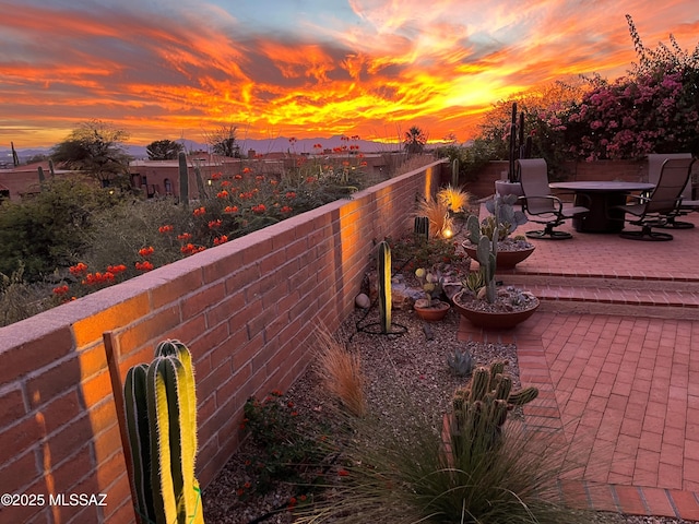 patio terrace at dusk featuring a fenced backyard and outdoor dining space