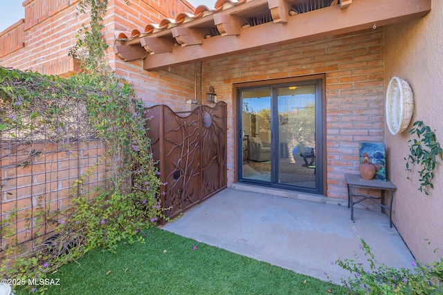 property entrance featuring a patio area, fence, brick siding, and stucco siding