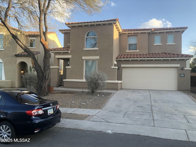 mediterranean / spanish-style house with an attached garage, a tiled roof, concrete driveway, and stucco siding