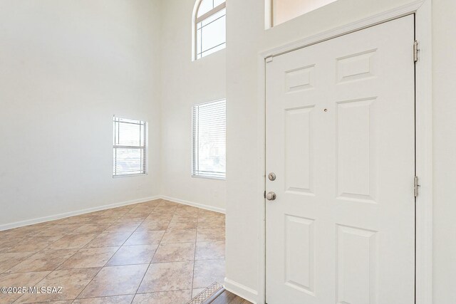 spare room featuring arched walkways, dark tile patterned flooring, a towering ceiling, and baseboards